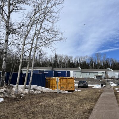 A fleet of storage containers occupies the Birchwood parking lot full of building materials. Photo by Kirsten Wisniewski